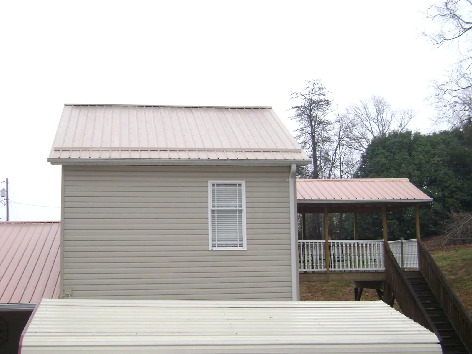 Tan metal roofs on a two story addition and attached porch, from a Roof Replacement job in Corvallis